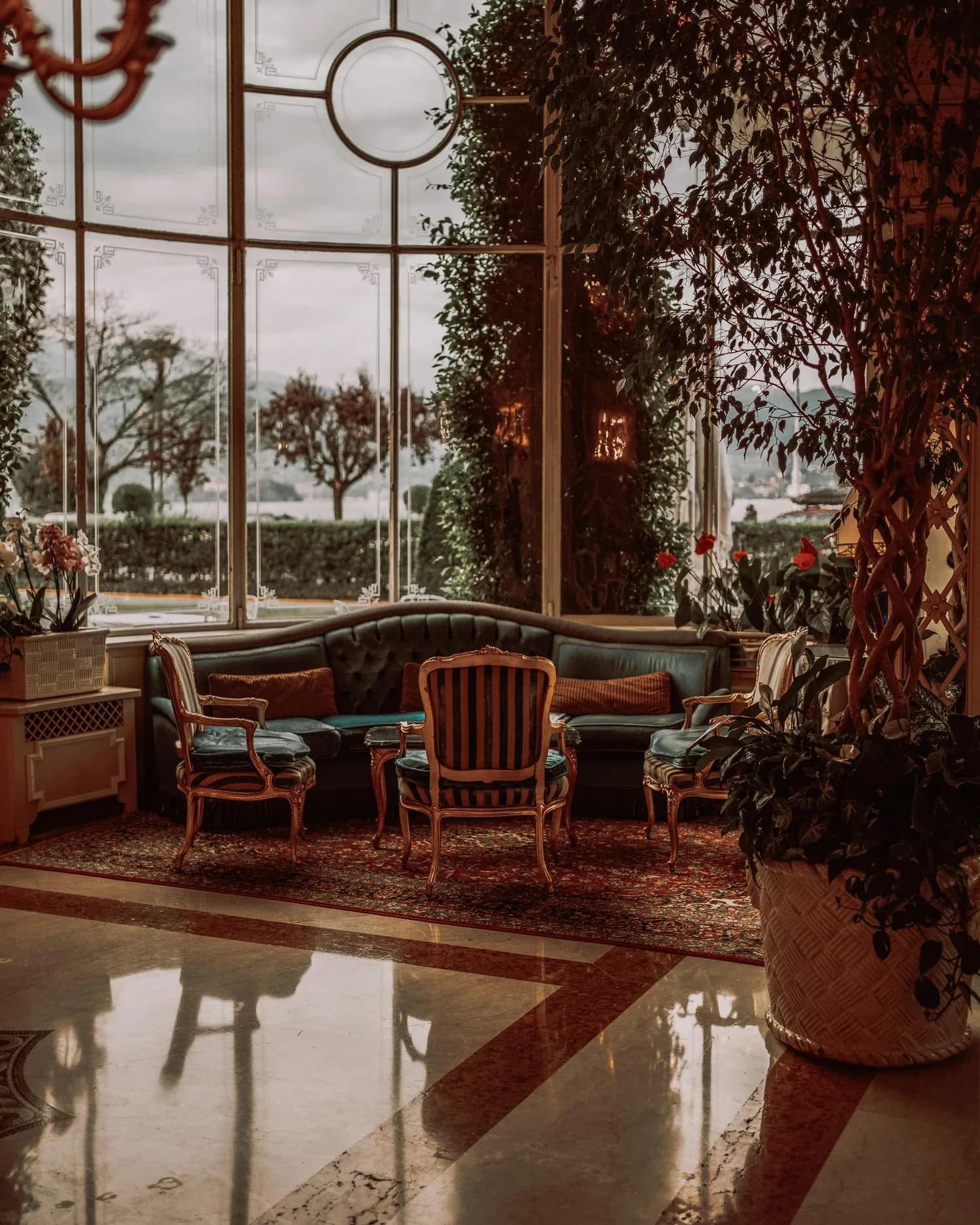 Salon d’hôtel indépendant avec fauteuils anciens et grande verrière